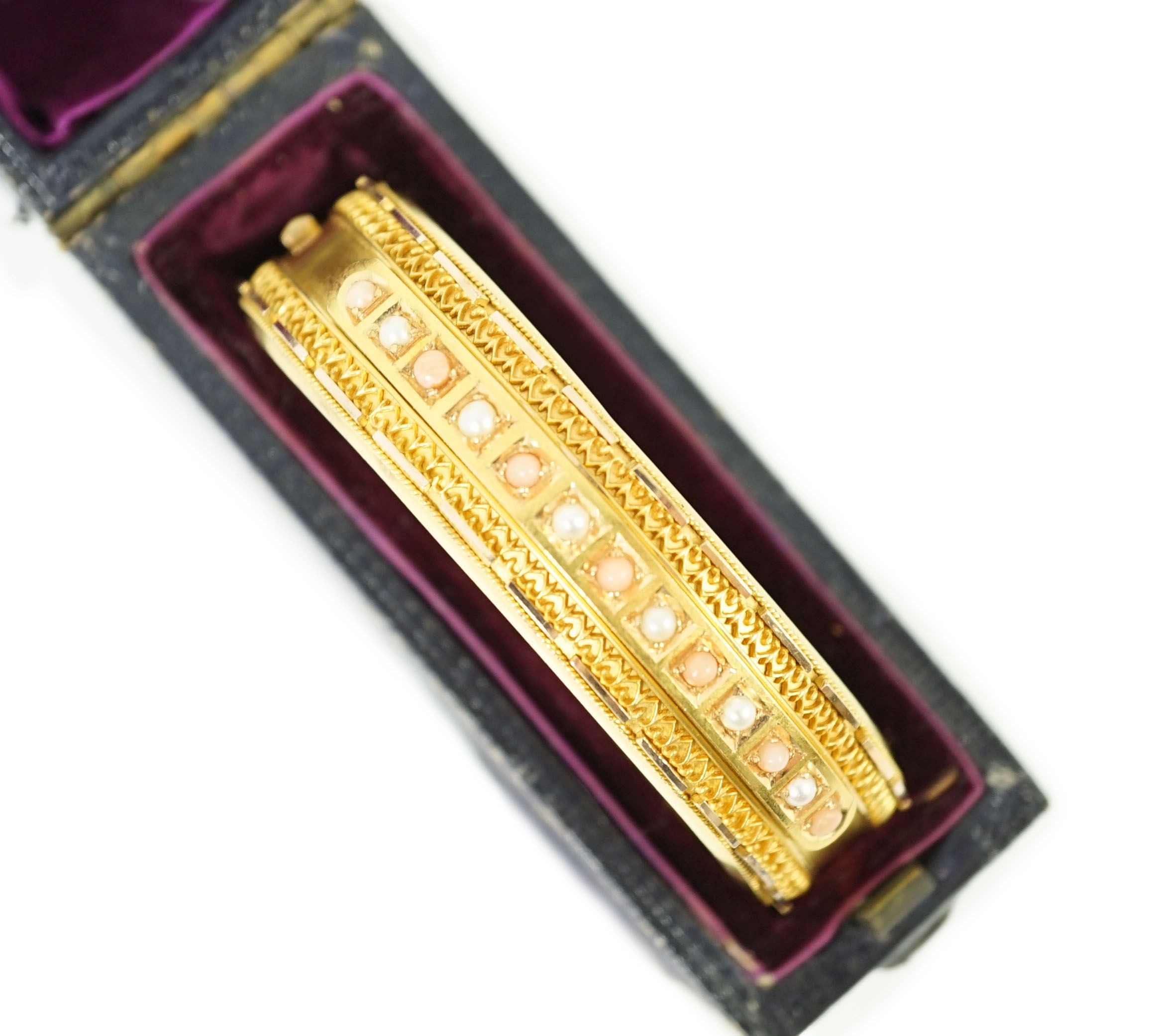 A late Victorian 15ct gold coral bead and seed pearl set part cannetile work hinged bangle